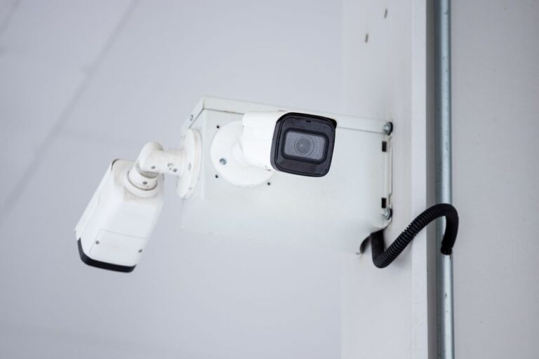 A white bullet-style security camera mounted on an exterior wall