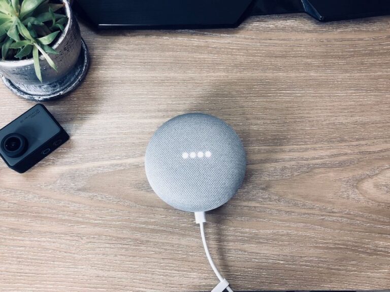 A Google Nest Mini smart speaker on a wooden desk