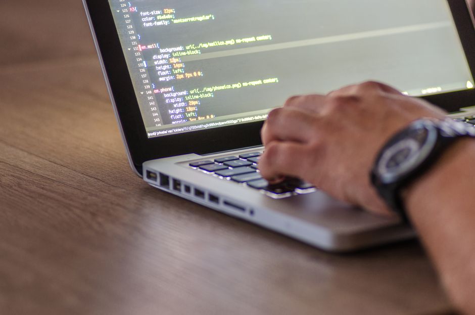 A person's hands typing on a laptop with home automation code on screen